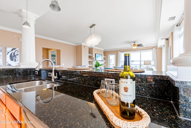 kitchen featuring sink, ceiling fan with notable chandelier, decorative light fixtures, dark stone counters, and ornamental molding