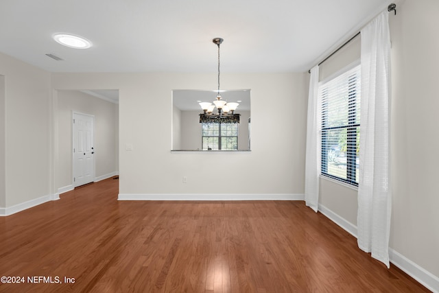 unfurnished dining area featuring a chandelier, plenty of natural light, and hardwood / wood-style floors