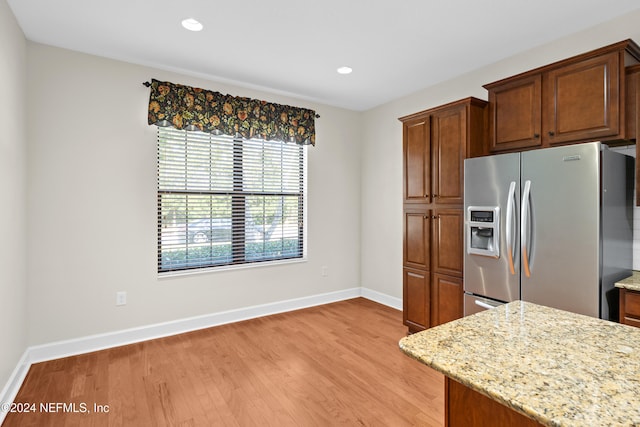 kitchen featuring stainless steel fridge, light stone countertops, and light hardwood / wood-style floors