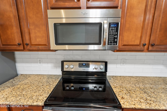 272 Hammocks Landing Dr, Ponte Vedra, FL 32081 - kitchen with appliances with stainless steel finishes, brown cabinetry, light stone countertops, and backsplash