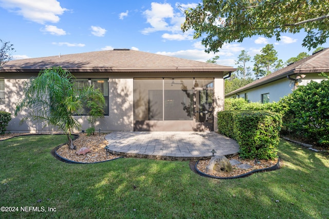 back of house featuring a patio area, a sunroom, and a lawn