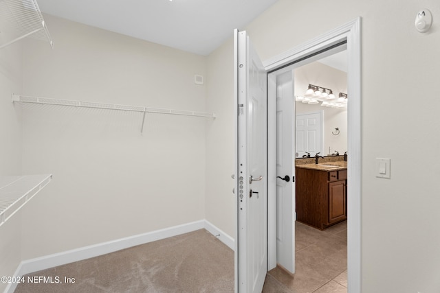 walk in closet featuring light tile patterned flooring and sink