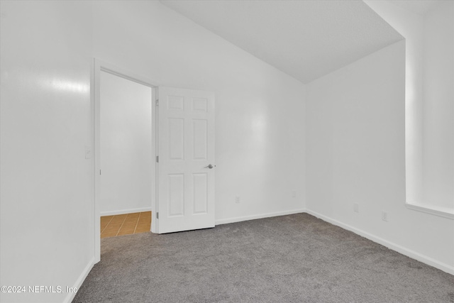 empty room featuring carpet and lofted ceiling