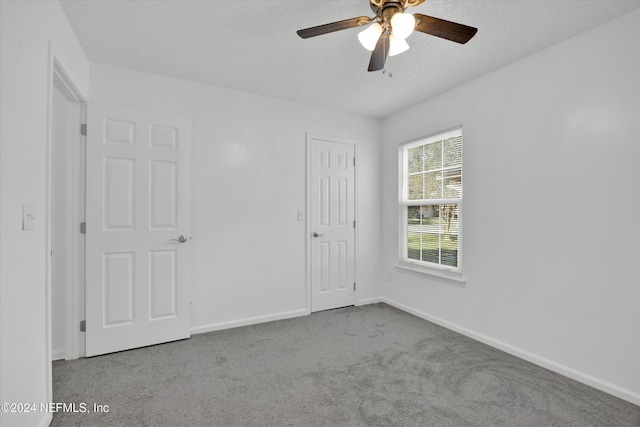 carpeted spare room featuring ceiling fan and a textured ceiling