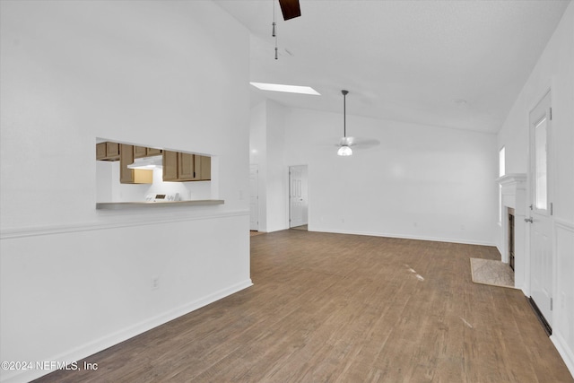 unfurnished living room with hardwood / wood-style floors, ceiling fan, a skylight, and high vaulted ceiling