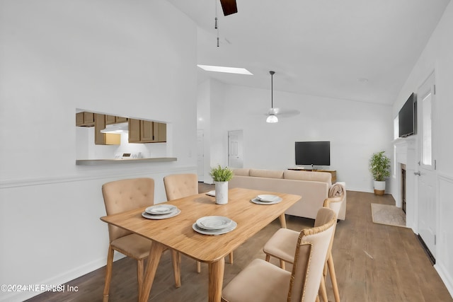 dining area featuring high vaulted ceiling, a skylight, hardwood / wood-style flooring, and ceiling fan