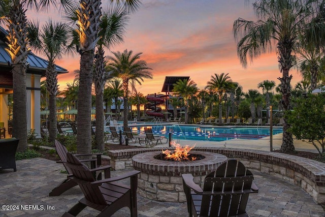 pool at dusk featuring a patio and a fire pit