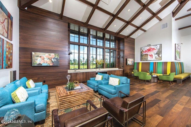 sitting room featuring beam ceiling, hardwood / wood-style flooring, high vaulted ceiling, and wooden walls