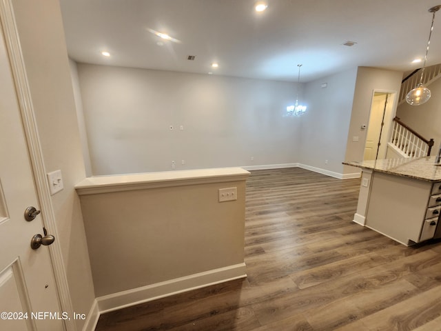 empty room with dark hardwood / wood-style flooring and a notable chandelier