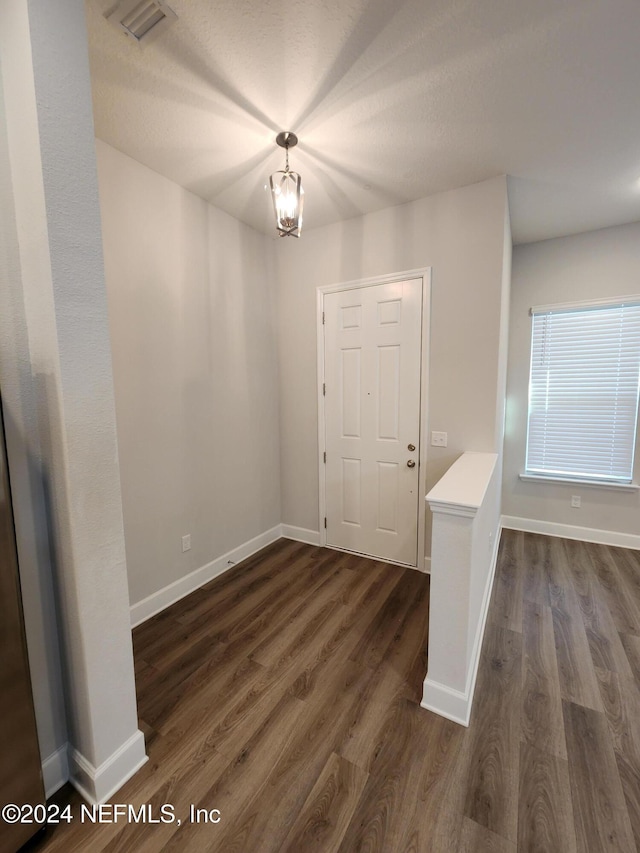 entryway with dark wood-type flooring and an inviting chandelier