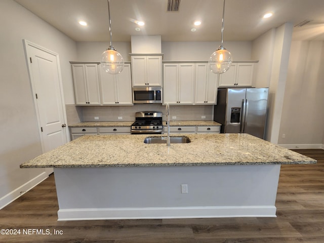 kitchen featuring a kitchen island with sink, white cabinets, light stone countertops, and appliances with stainless steel finishes