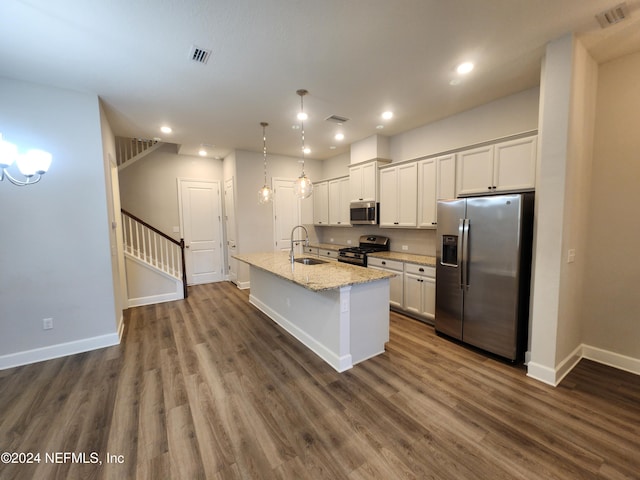 kitchen with a kitchen island with sink, sink, dark hardwood / wood-style floors, appliances with stainless steel finishes, and light stone counters