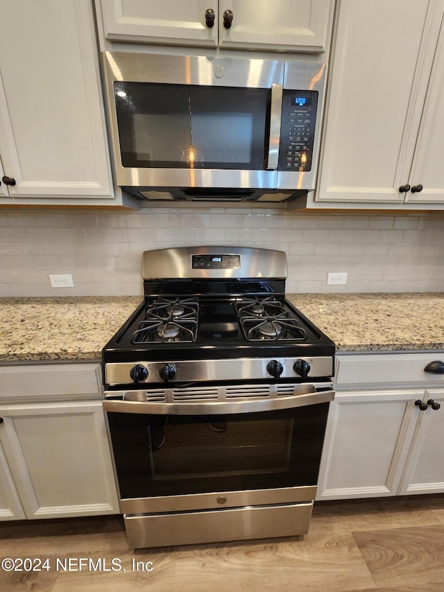 kitchen with light stone countertops, white cabinets, and stainless steel appliances