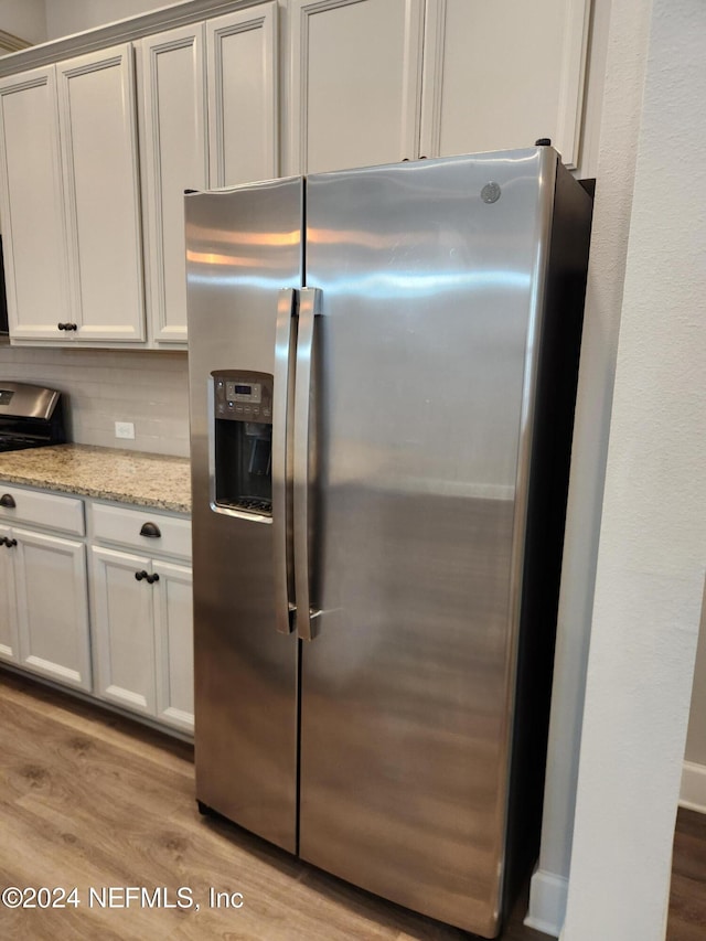 kitchen featuring stainless steel fridge with ice dispenser, light hardwood / wood-style flooring, white cabinets, and light stone countertops