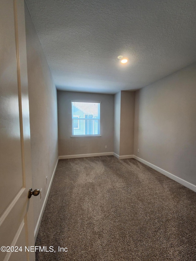 spare room with a textured ceiling and carpet floors