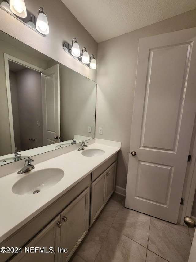 bathroom featuring tile patterned flooring, vanity, and a textured ceiling