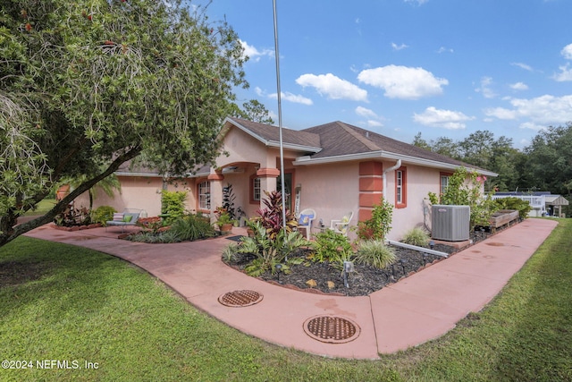 view of front of home with central AC and a front yard