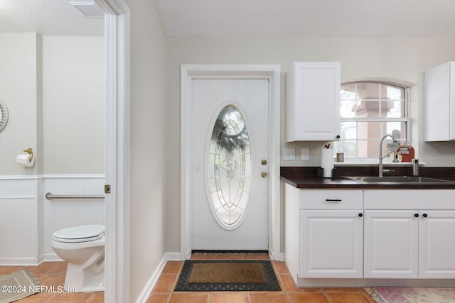 kitchen featuring light tile patterned flooring, a textured ceiling, sink, and white cabinets