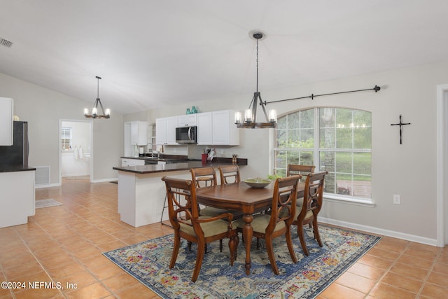 dining room with sink, light tile patterned floors, lofted ceiling, and a chandelier