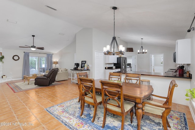 tiled dining space featuring ceiling fan with notable chandelier and vaulted ceiling