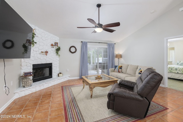 tiled living room with ceiling fan, vaulted ceiling, and a fireplace