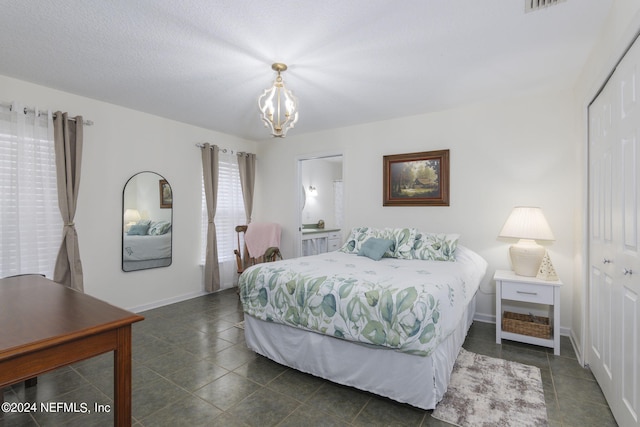 tiled bedroom with a closet, a textured ceiling, and a chandelier