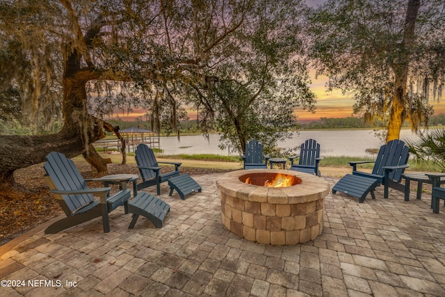 patio terrace at dusk with a water view and an outdoor fire pit