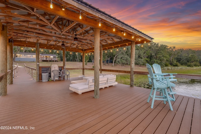 deck at dusk with a gazebo and a water view