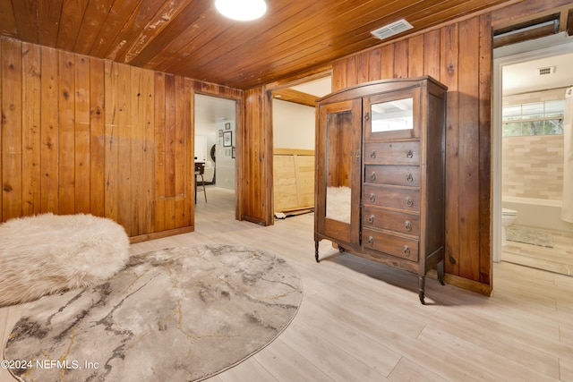 interior space featuring light hardwood / wood-style flooring, ensuite bathroom, wooden walls, and wooden ceiling