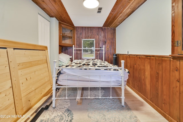 bedroom featuring hardwood / wood-style floors and wooden walls