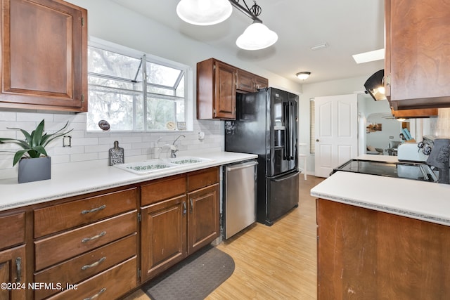 kitchen with black refrigerator with ice dispenser, light wood-type flooring, dishwasher, range, and decorative light fixtures