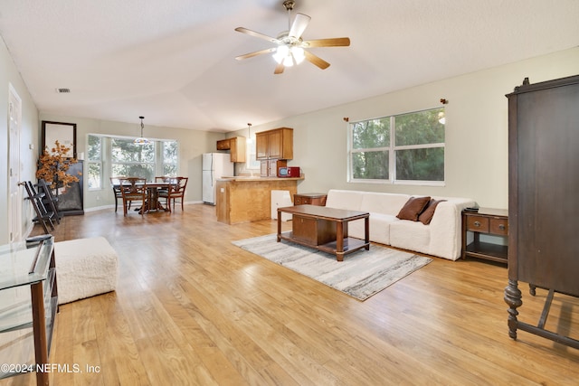 living room featuring vaulted ceiling, light hardwood / wood-style flooring, and ceiling fan