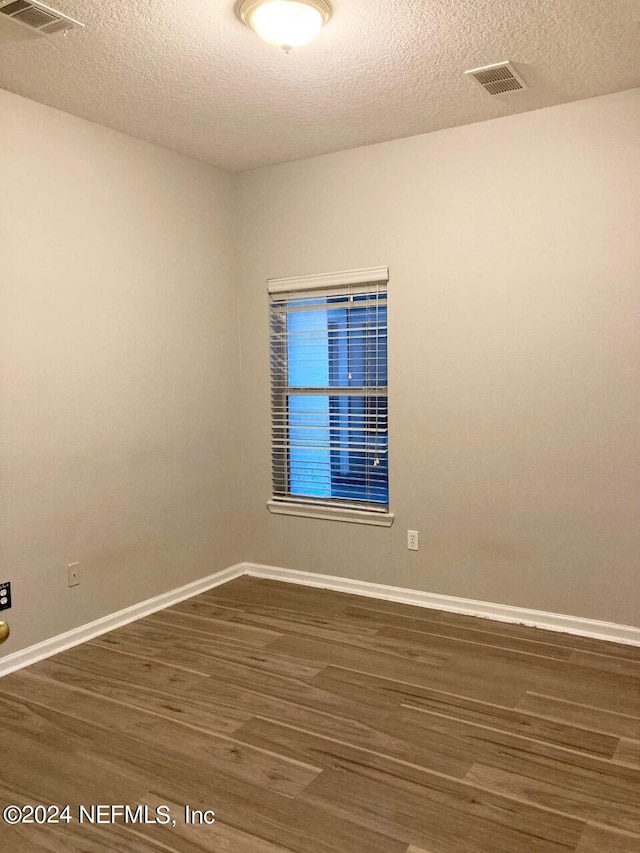 empty room featuring a textured ceiling and dark hardwood / wood-style floors