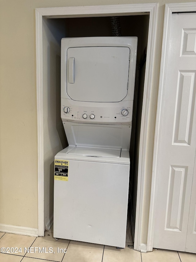 laundry area with light tile patterned flooring and stacked washer and clothes dryer