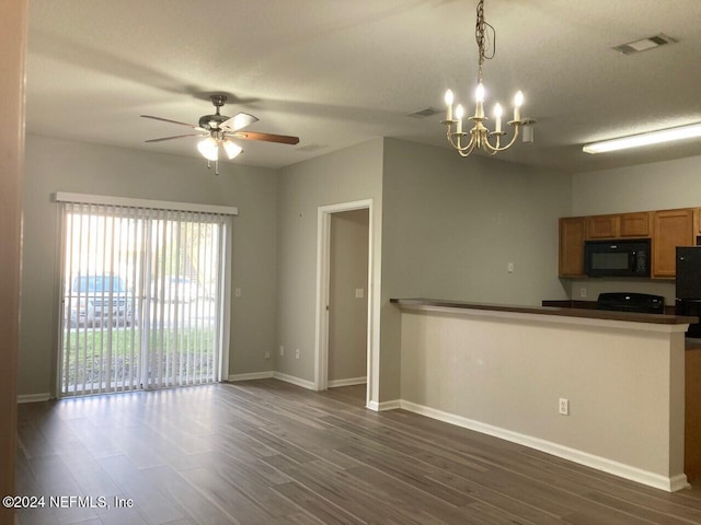 kitchen featuring black appliances, ceiling fan with notable chandelier, kitchen peninsula, pendant lighting, and dark wood-type flooring