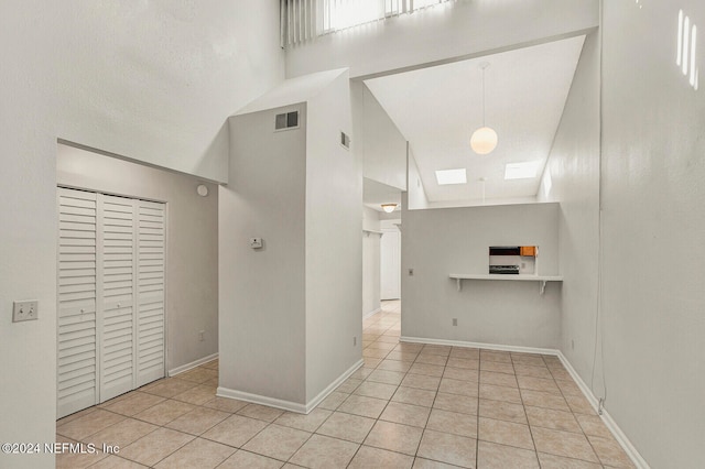 interior space with light tile patterned flooring and high vaulted ceiling