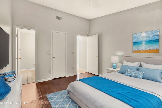 bedroom featuring ensuite bathroom and dark hardwood / wood-style flooring