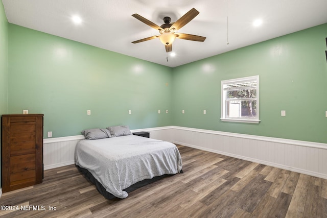 bedroom featuring a wainscoted wall, ceiling fan, and wood finished floors