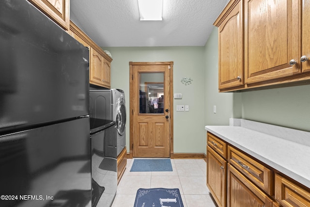 laundry room with light tile patterned floors, cabinet space, a textured ceiling, independent washer and dryer, and baseboards