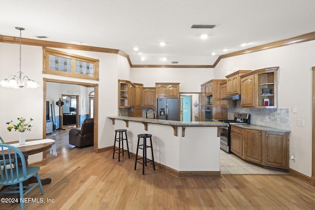 kitchen with a kitchen bar, light hardwood / wood-style flooring, stainless steel appliances, and decorative light fixtures