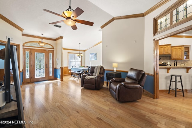 living room with ceiling fan with notable chandelier, light hardwood / wood-style floors, ornamental molding, and lofted ceiling