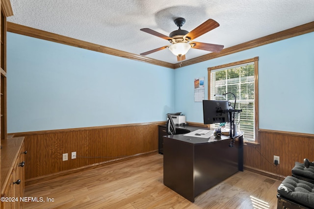 office area with a textured ceiling, wooden walls, light wood-style floors, ornamental molding, and wainscoting