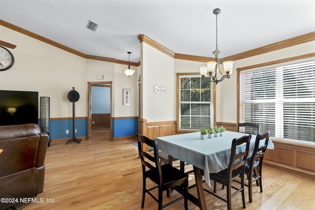 dining space featuring a chandelier, a textured ceiling, light wood-type flooring, and crown molding