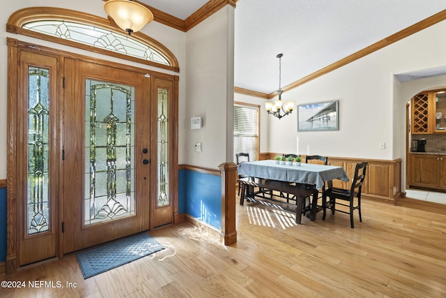 foyer featuring ornamental molding, wainscoting, an inviting chandelier, and light wood-style floors