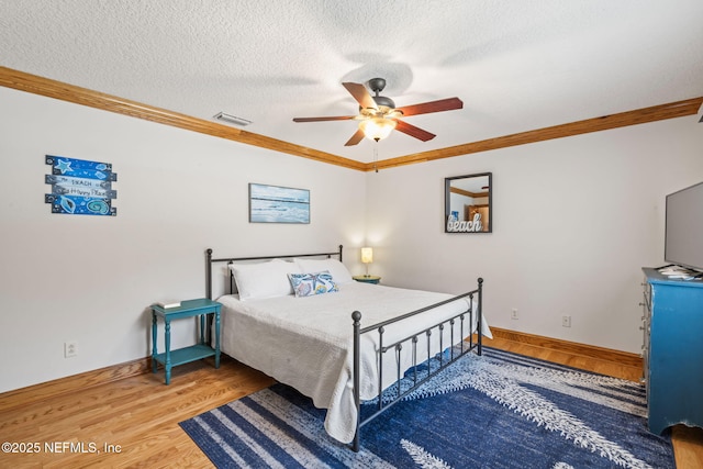 bedroom with visible vents, ornamental molding, ceiling fan, a textured ceiling, and wood finished floors