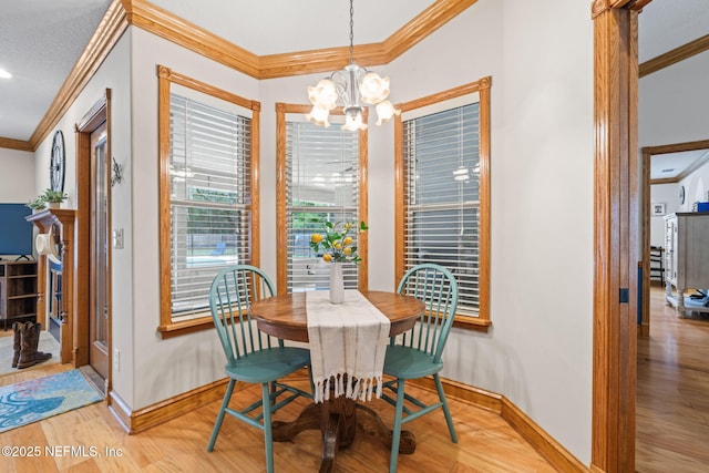 dining space with light wood-style flooring, ornamental molding, a chandelier, and baseboards