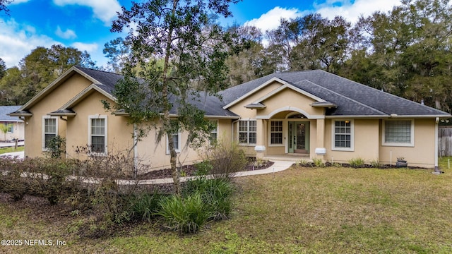 ranch-style house with stucco siding, a shingled roof, and a front yard