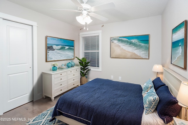 bedroom featuring a textured ceiling, light hardwood / wood-style flooring, a closet, and ceiling fan