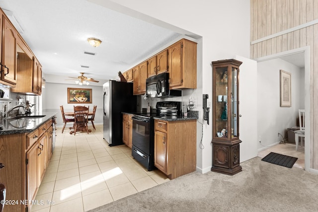 kitchen featuring black appliances, sink, ceiling fan, dark stone counters, and light colored carpet