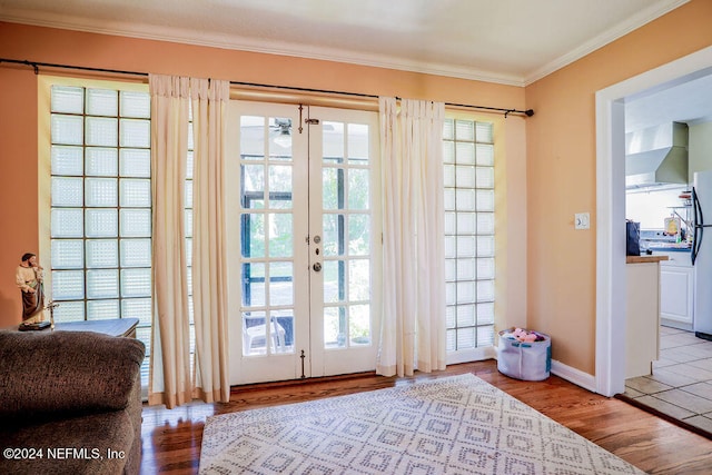 doorway featuring french doors, ornamental molding, and light wood-type flooring